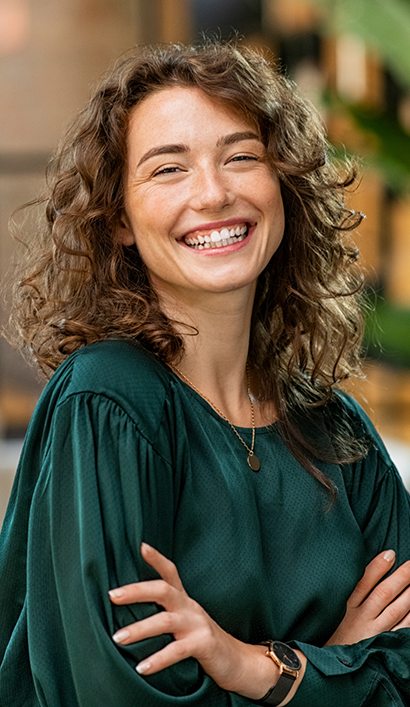 Woman in green blouse smiling after seeing cosmetic dentist in Peabody