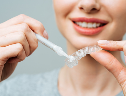 Person placing teeth whitening gel in a dental tray