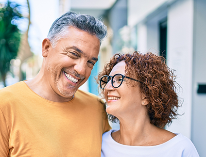 Man and woman smiling at each other with city buildings in background