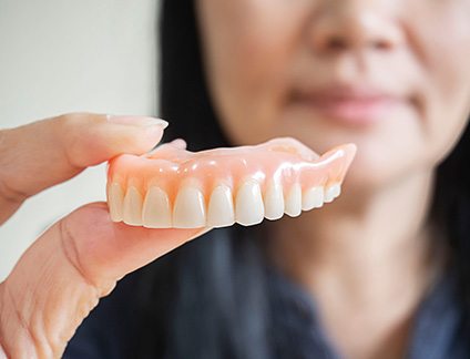 Person holding an upper full denture