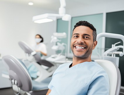 Younger man smiling in the dentist’s chair with dentures