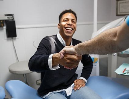 Man smiling while shaking hands with his dentist