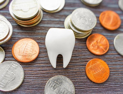a tooth surrounded by coins on a wooden table