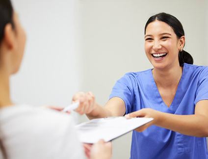 a dental office front desk member smiling at a patient
