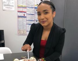 Woman in black blazer smiling while sitting at desk in dental office