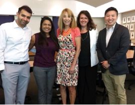 Five people in professional attire standing in dental office