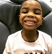 Young boy grinning while sitting in dental chair