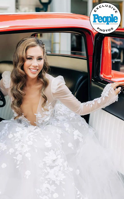 Smiling woman in wedding dress stepping out of a car