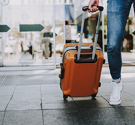 Person carrying a wheeled suitcase behind them in an airport