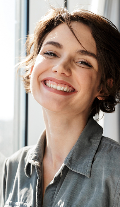 Young woman with short brown hair smiling after replacing missing teeth in Peabody