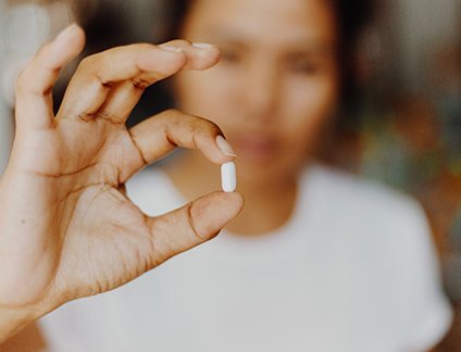 Closeup of a woman holding a pill