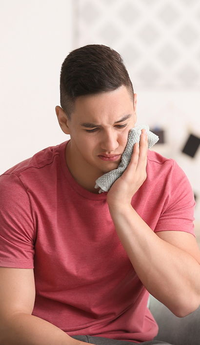 Man holding a cold compress to his cheek before root canal treatment