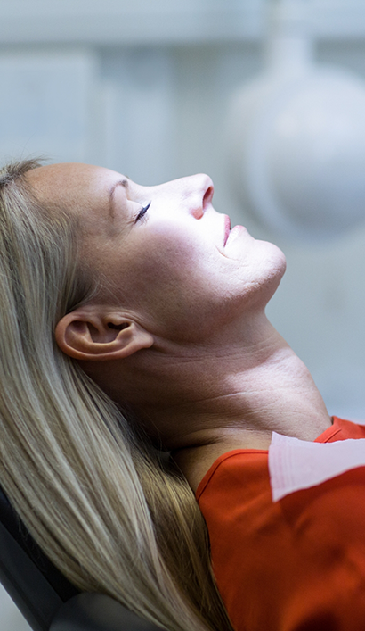 Woman relaxing in dental chair with eyes closed thanks to sedation dentistry