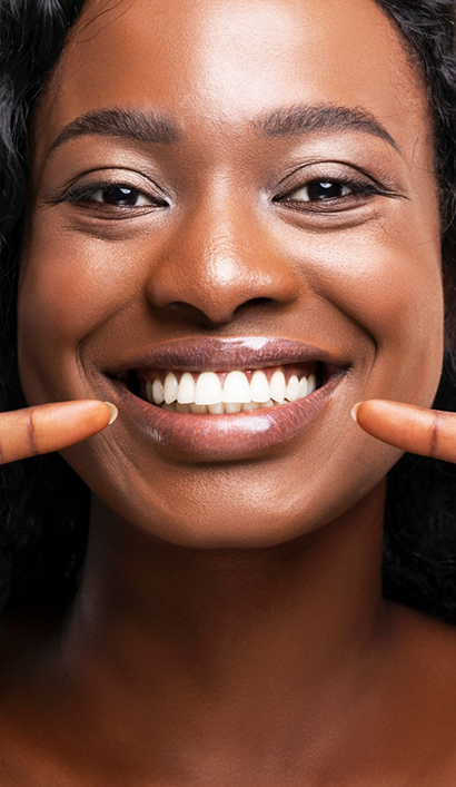 Close up of a woman pointing to her flawless smile