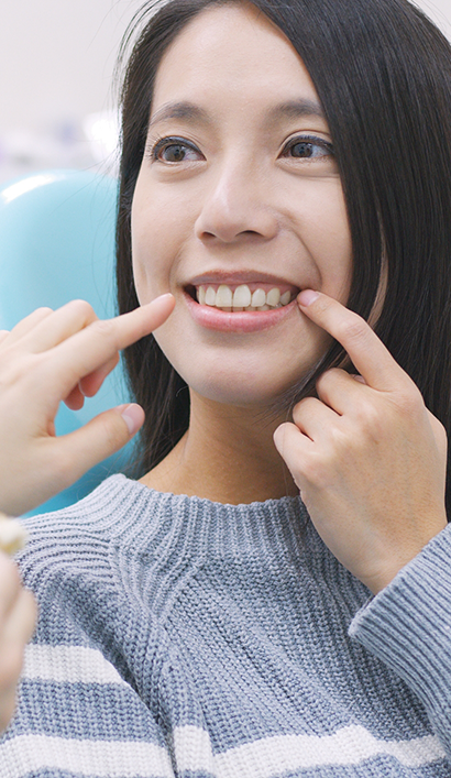 Dental patient pointing to her smile after tooth extractions in Peabody